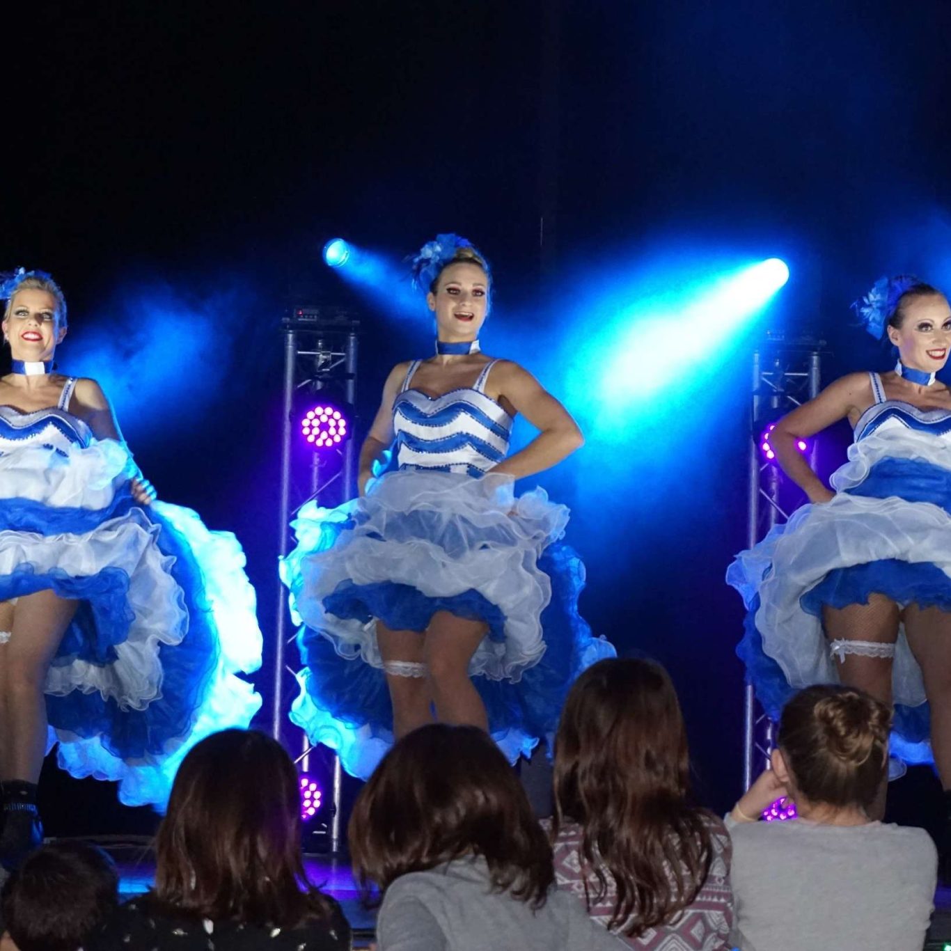 Danseuses de cabaret Danseuses en costumes bleu et blanc, performe sous des éclairages dynamiques.